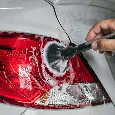 Car detailing brush cleaning tail light.